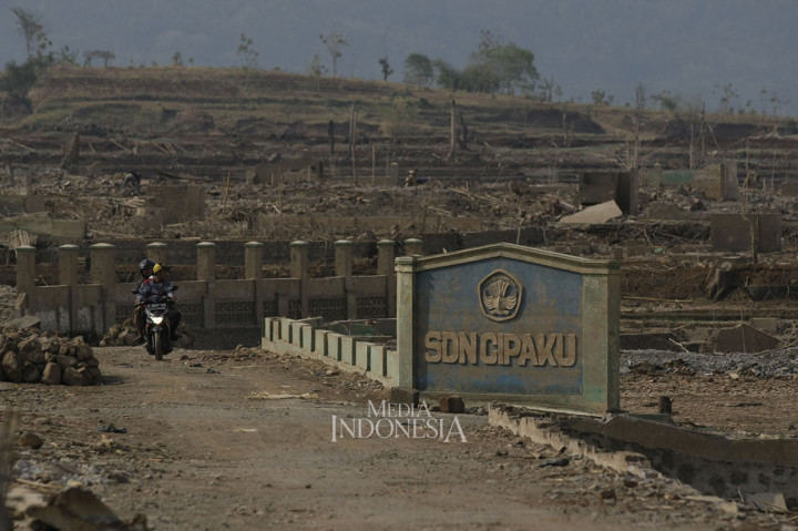 Warga melintas diantara puing sisa bangunan sekolah yang dulunya merupakan wilayah Desa Cipaku, Kecamatan Darmaraja, Kabupaten Sumedang, Jawa Barat.