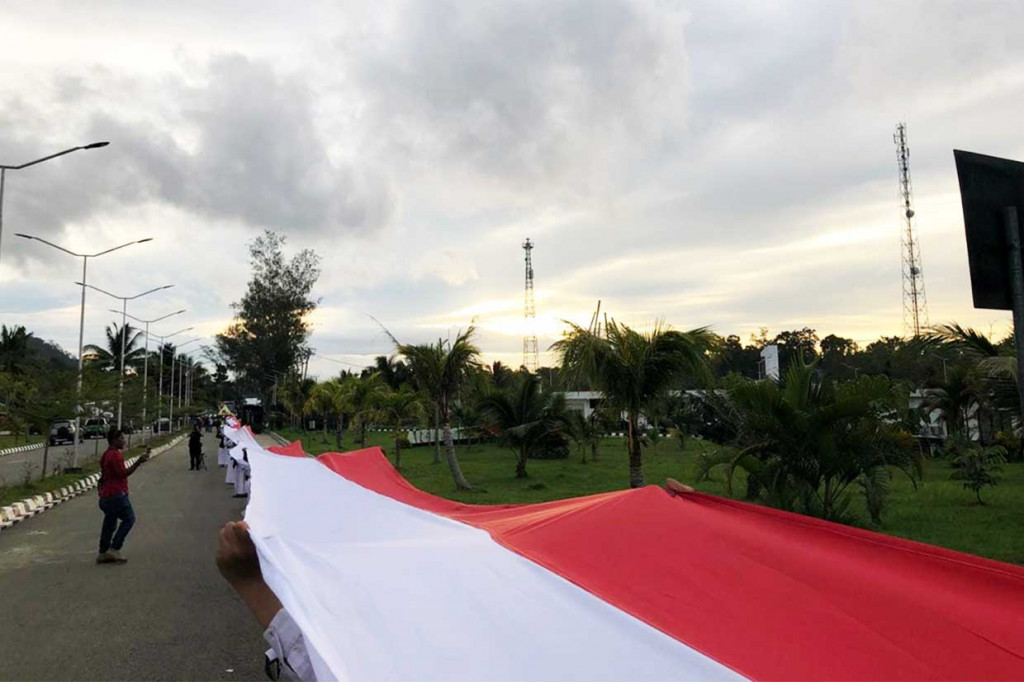 Tim Kirab Satu Negeri Gerakan Pemuda Ansor bersama para siswa dan anggota ormas membentangkan kain Merah Putih sepanjang 1.500 meter di perbatasan RI-Papua Nugini (PNG), Skouw-Wutung, Distrik Muara Tami, Kota Jayapura, Papua, Senin, 17 September 2018 sore.