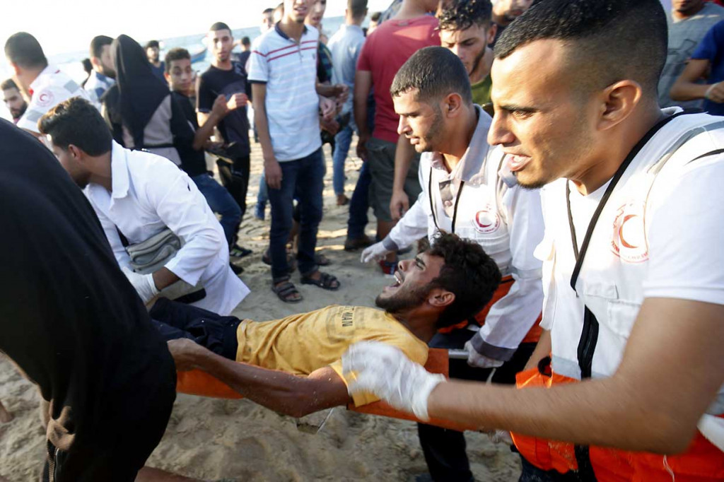 Petugas penyelamat Palestina mengevakuasi demonstran yang terluka pascabentrok dengan tentara Israel di sebuah pantai di Beit Lahia, dekat perbatasan maritim dengan Israel, Senin, 17 September 2018.