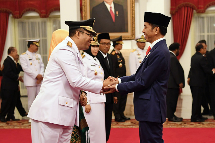 Presiden Joko Widodo (kanan) memberi ucapan selamat kepada Gubernur Nusa Tenggara Barat (NTB) Zulkifliemansyah (kiri) disaksikan Wakil Gubernur Sitti Rohmi Djalilah (kedua kiri) seusai pelantikan di Istana Negara Jakarta.
