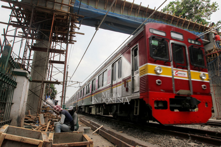 Commuter Line melintas dibawah Jembatan Penyeberangan Orang (JPO) yang sedang dibangun di kawasan stasiun Tebet, Jakarta.
