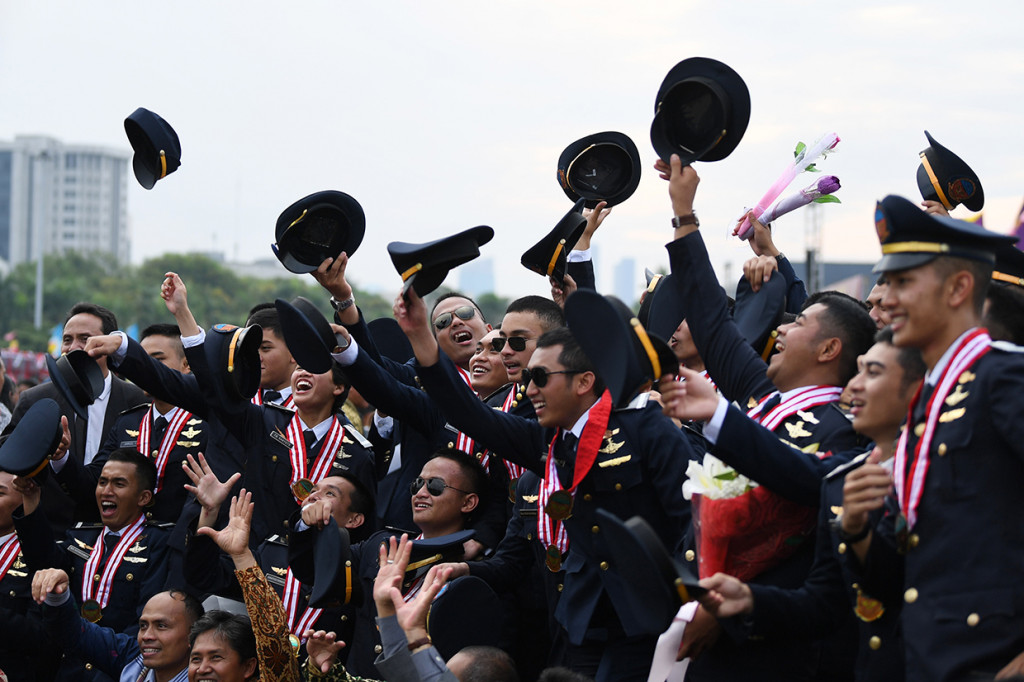 Peserta melempar topi seusai Pelantikan Terpadu Perwira Transportasi Indonesia 2018 di kawasan Monas, Jakarta.