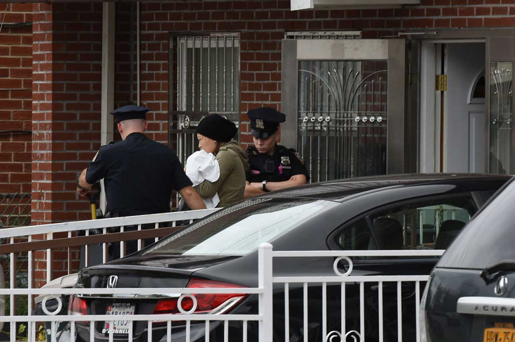 Seorang perempuan menggendong bayinya keluar dari pusat penitipan anak di daerah Flushing, Queens, Kota New York, tempat terjadinya penikaman, Jumat, 21 September waktu setempat.