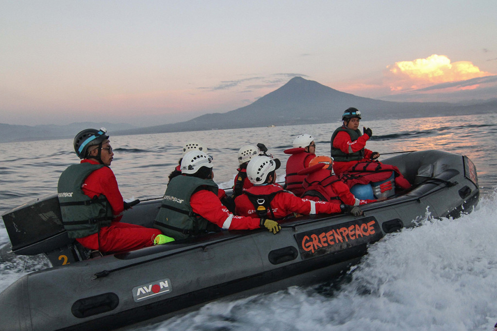 Aktivis Greenpeace menaiki perahu karet saat melakukan aksi di Bitung, Sulawesi Utara.
