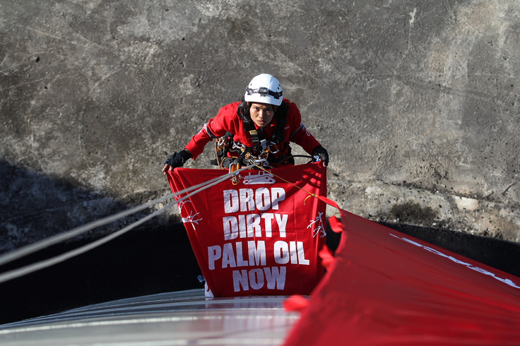 Aktivis Greenpeace membentangkan spanduk bertuliskan 