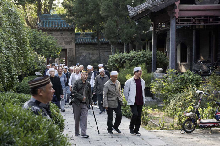 Umat muslim berjalan ke luar areal masjid usai menjalankan ibadah salat di Mesjid Agung, di kawasan komunitas muslim di Xi'an.

