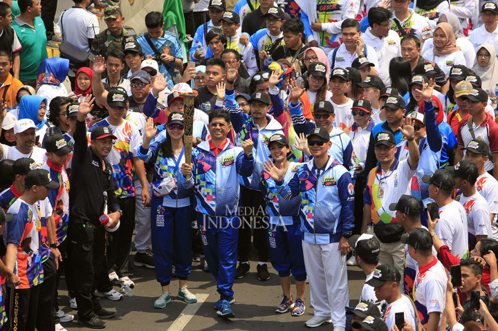 Ketua pelaksana Asian Paragames Raja Sapta Oktohari (kanan) dan sejumlah artis dan atlet menemani Wakil Ketua KPK Laode M Syarief (tengah) membawa obor ketika acara pawai obor api Asian Para games 2018 ketika melintas di Jalan MH Thamrin, Jakarta.