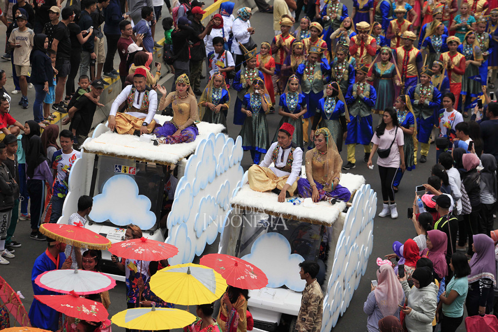 Peserta dengan menggunakan pakaian tradisional turut memeriahkan pawai obor api Asian Para games 2018 ketika melintas di Jalan MH Thamrin, Jakarta.