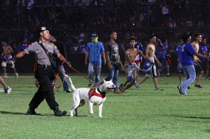 Petugas Satuan K-9 dari Kepolisian berusaha menghalau oknum suporter Arema FC (Aremania) yang memasuki lapangan.