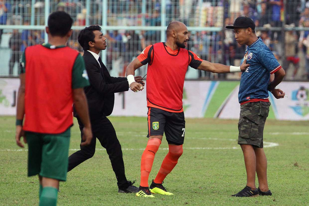 Pesepakbola Persebaya Alfonsius Kelvan (tengah) bersitegang dengan oknum suporter Arema FC (Aremania) yang memasuki lapangan saat istirahat babak pertama.