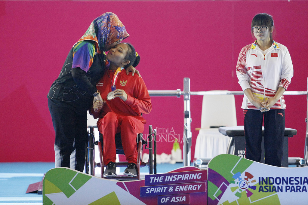 Wakil Ketua Umum Indonesia Asian Para Games 2018 (INAPGOC) Sylviana Murni memeluk dan mencium lifter Indonesia Ni Nengah Widiasih saat memberikan medali perak pada Powerlifting Kelas 41 kg Asian Para Games 2018 di Balkai Sudirman, Jakarta.