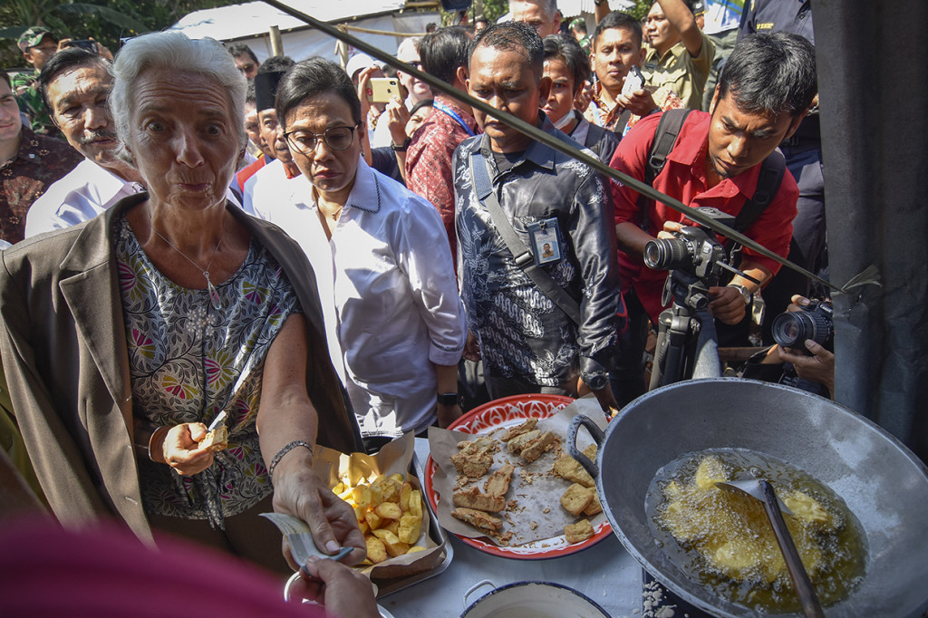 Direktur Pelaksana International Monetary Fund (IMF) Christine Lagarde (kedua kiri) membeli gorengan saat mengunjungi korban gempa di Desa Guntur Macan, Kecamatan Gunungsari, Lombok Barat, NTB.