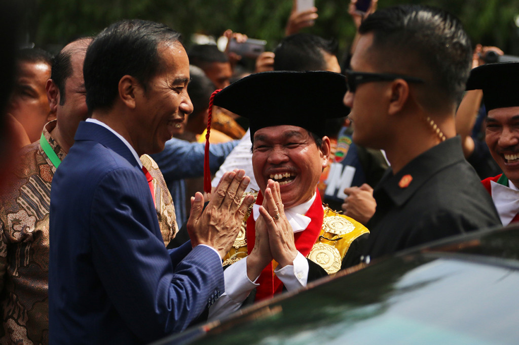 Presiden Joko Widodo (kiri) dan Rektor Universitas Sumatera Utara (USU) Runtung Sitepu (tengah) saling memberi salam usai menyampaikan orasi di kampus USU, Medan, Sumatra Utara.