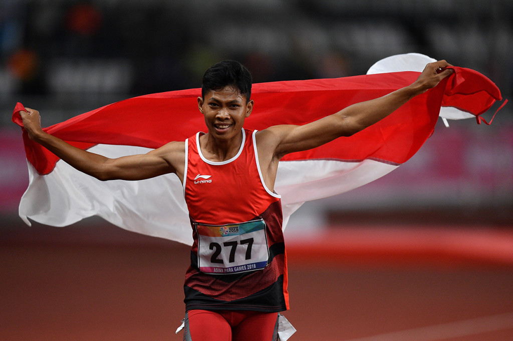 Sprinter Indonesia Sapto Yogo Purnomo berlari sambil membawa bendera Merah-Putih usai menjuarai final 100 meter putra T37 Asian Para Games di Stadion Utama Gelora Bung Karno, Senayan, Jakarta.