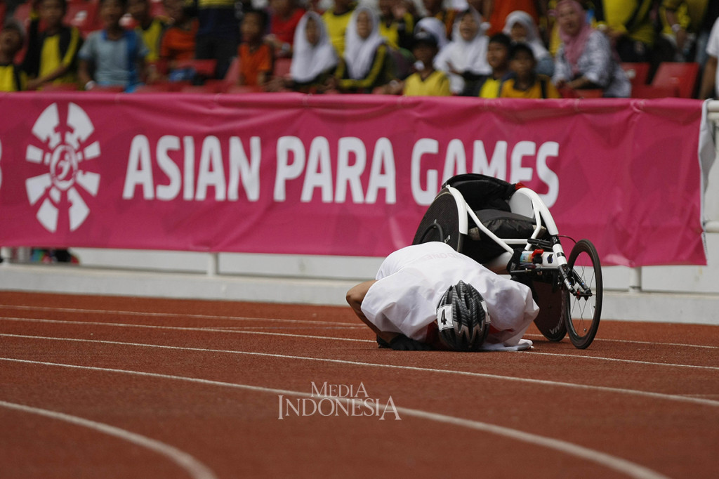 Sprinter kursi roda Indonesia Jaenal Aripin bersujud merayakan pencapaiannya setelah finis kedua dalam final lari kursi roda 200 meter putra T54 Asian Para Games 2018 di Stadion Utama GBK, Senayan, Jakarta.