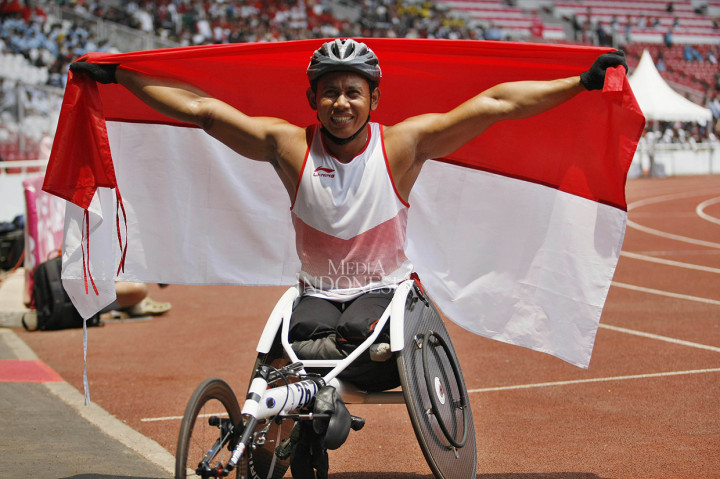 Sprinter kursi roda Indonesia Jaenal Aripin melakukan selebrasi setelah finis kedua dalam final lari kursi roda 200 meter putra T54 Asian Para Games 2018 di Stadion Utama GBK, Senayan, Jakarta.