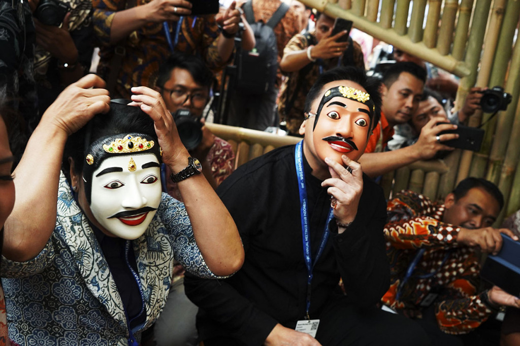 Menteri BUMN Republik Indonesia Rini Soemarno (kiri) bersama Kepala Badan Ekonomi Kreatif Triawan Munaf (kanan) memakai topeng yang diukir oleh seniman Bali usai meresmikan Paviliun Indonesia pada rangkaian Pertemuan Tahunan IMF - World Bank Group 2018 di Nusa Dua, Bali. Antara Foto/ICom/AM IMF-WBG/Jefri Tarigan