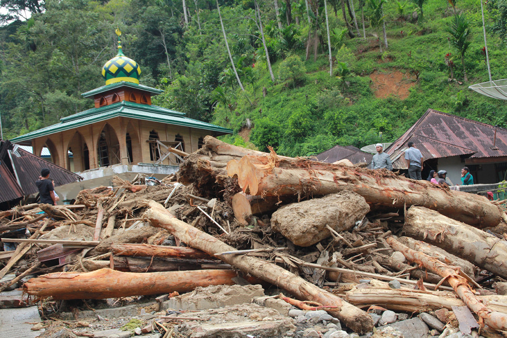Beberapa warga berada di antara kayu yang terbawa arus sungai pascabanjir bandang yang terjadi, di Desa Muara Saladi, Kecamatan Ulu Pungkut, Mandailing Natal, Sumatra Utara, Sabtu (13/10). 