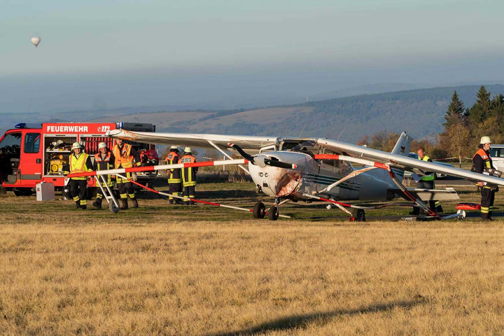 Petugas pemadam kebakaran berdiri di dekat pesawat ringan Cessna yang menabrak sekelompok penonton di Gersfeld, Jerman, Minggu, 14 Oktober 2018 waktu setempat.