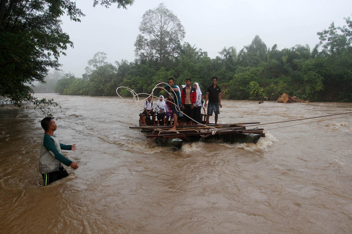 Sejumlah pelajar menggunakan perahu getek untuk menyeberang sungai Batang Batahan di Jorong Lubuk Gobing, Nagari Silaping, Kecamatan Ranah Batahan, Kabupaten Pasaman Barat, Sumatera Barat.