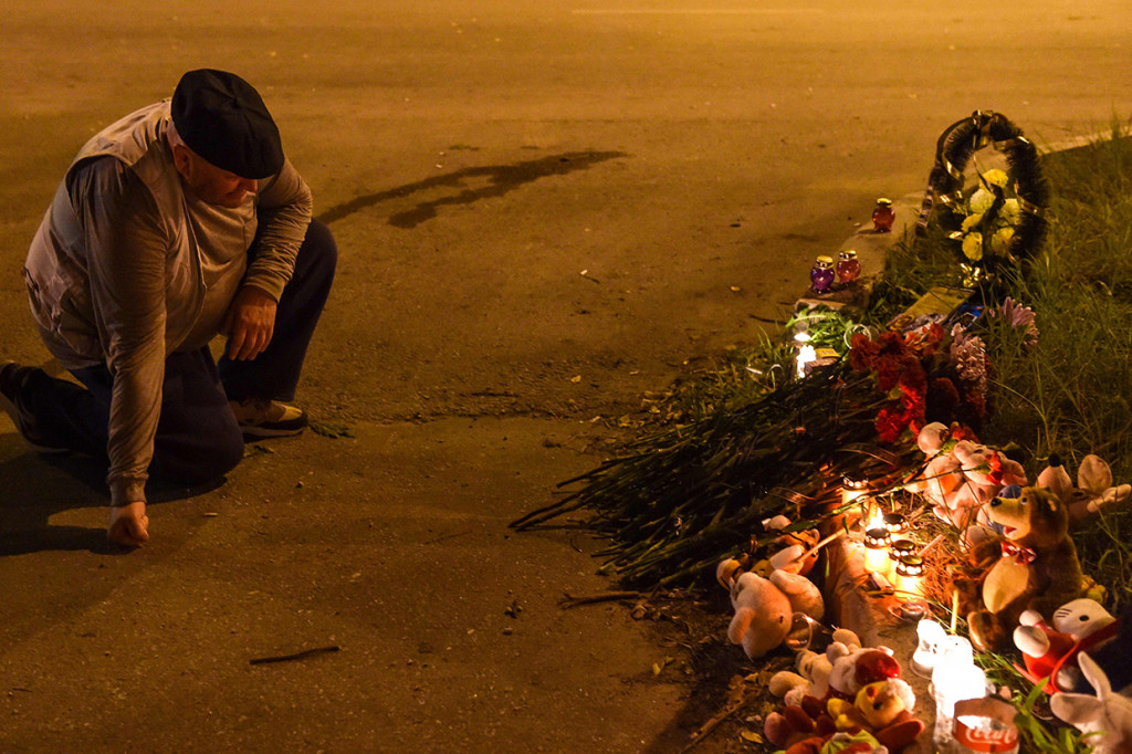 Seorang pria berlutut sambil meletakkan bunga di dekat sebuah perguruan tinggi di Kerch, Crimea. Afp Photo/Andrey Petrenko