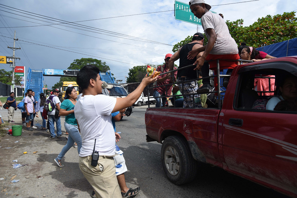 Warga setempat memberikan makanan bagi pengungsi yang lewat. Afp Photo/Orlando Estrada