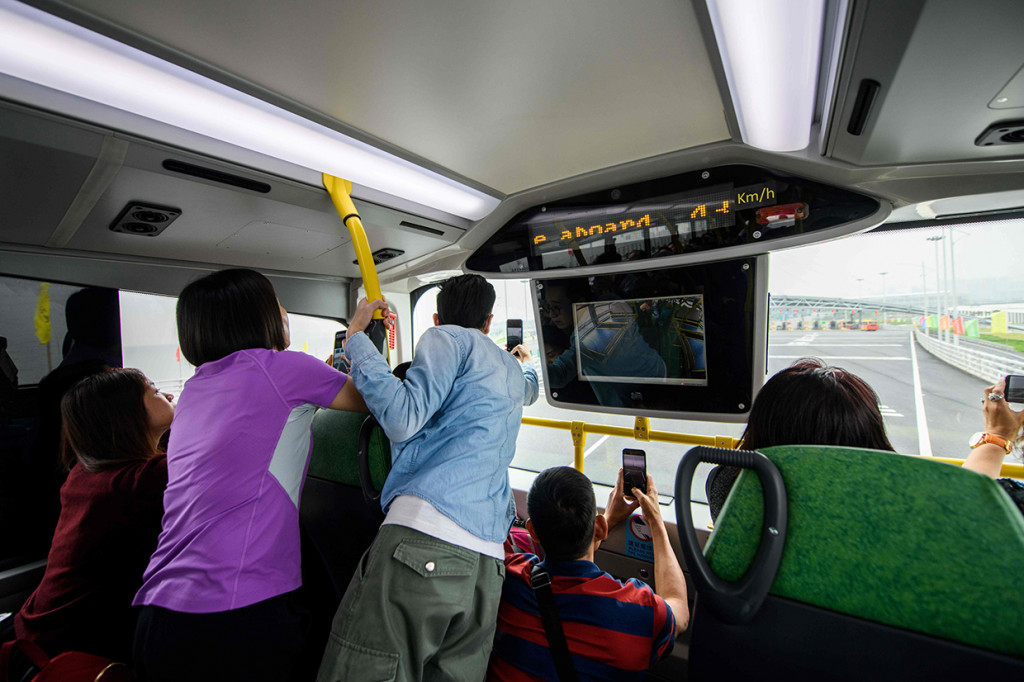 Para wisatawan mengabadikan gambar dari dalam bus yang membawanya menyusuri jembatan terpanjang di dunia.