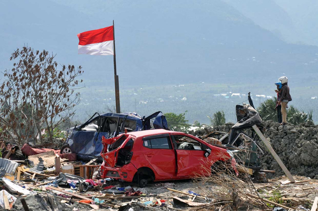 Warga melihat mobil yang hancur akibat bencana gempa dan pencairan tanah di Petobo, Palu, Sulawesi Tengah, Jumat, 26 Oktober 2018.