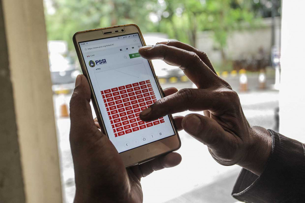 Warga melihat pembelian tiket secara online di website PSSI setelah antre secara offline untuk mendapatkan tiket pertandingan perempat final Piala Asia U-19 antara Indonesia dan Jepang.