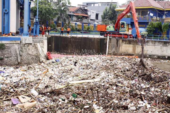 Petugas kebersihan membersihkan sampah yang menumpuk di Pintu Air Manggarai, Jakarta. 