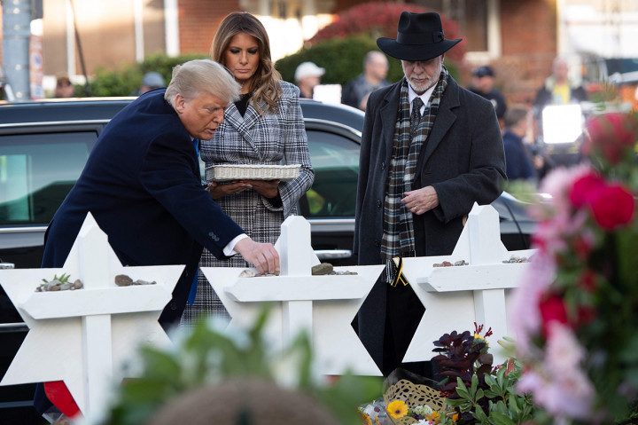 Melania Trump menaruh bunga dan presiden meletakkan batu kecil di atas foto masing-masing korban, sebagai doa belasungkawa sesuai tradisi Yahudi. Afp Photo/Saul Loeb
