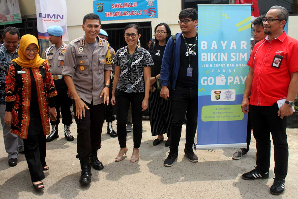 Kapolres Metro Bekasi Kota Kombes Indarto (kanan) mendengarkan penjelasan dari Government Relations and Policy GO-PAY Brigitta Ratih Aryanti (kedua kanan) saat peluncuran sistem pembayaran non tunai surat izin mengemudi (SIM), di Mapolres Metro Bekasi Kota, Bekasi, Jawa Barat, Jumat, 2 November 2018. 