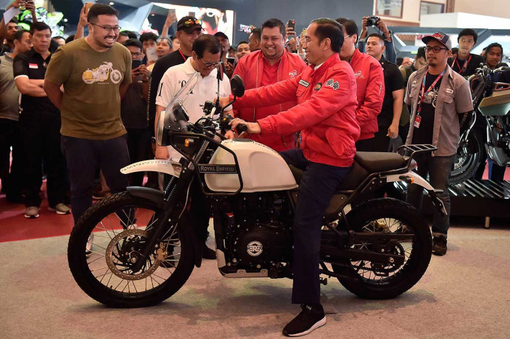 Mengenakan  jaket merah terang yang bagian belakangnya bertuliskan 'Bulls Syndicate, Motorcycle Worshiper' dengan huruf putih, Jokowi mencoba motor Royal Enfield berbadan putih dengan jok hitam.