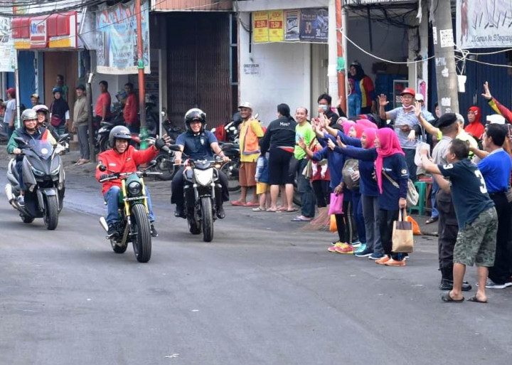 Membalas sapaan warga yang kaget mengetahui bahwa Presiden Jokowi sedang melintas dengan bersepeda motor.