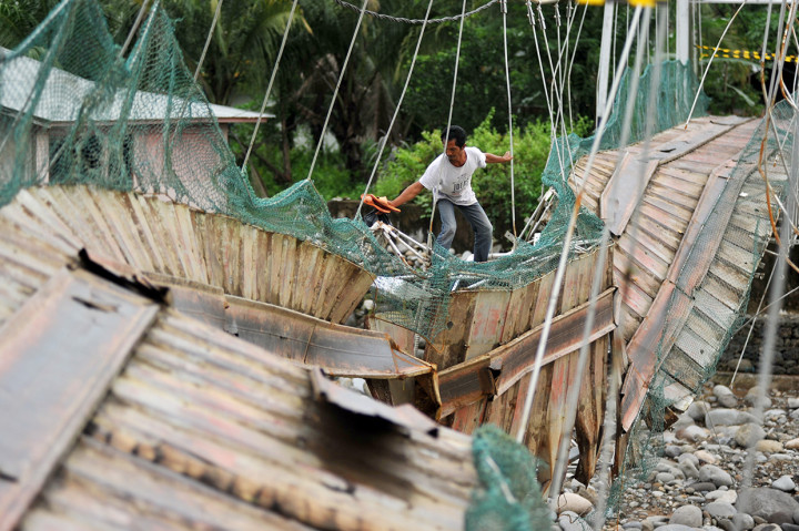 Warga melewati jembatan yang rusak di Kelurahan Baringin, Lubuk Kilangan, Padang, Sumatera Barat.