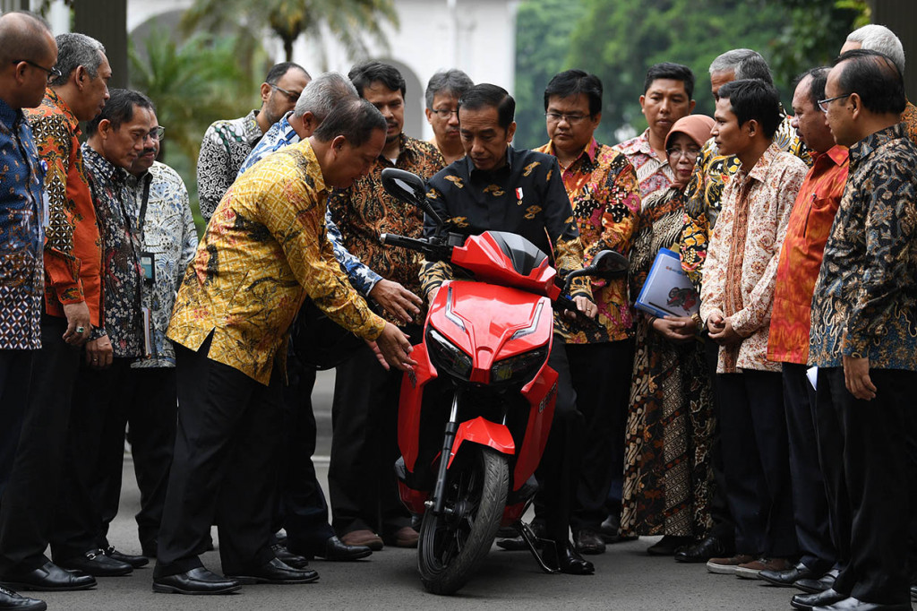 Presiden Joko Widodo (tengah) mendengarkan penjelasan dari Menristekdikti M Nasir (kelima kiri) sebelum menjajal motor listrik buatan dalam negeri 'Gesits' seusai melakukan audiensi dengan pihak-pihak yang terlibat proses produksi di halaman tengah Istana Kepresidenan, Jakarta.
