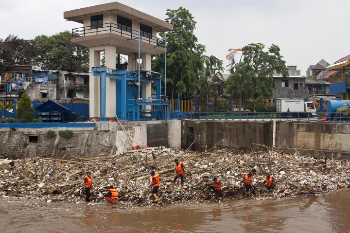 Petugas Dinas Kebersihan DKI Jakarta membersihkan sampah yang menumpuk di pintu air Manggarai, Jakarta.