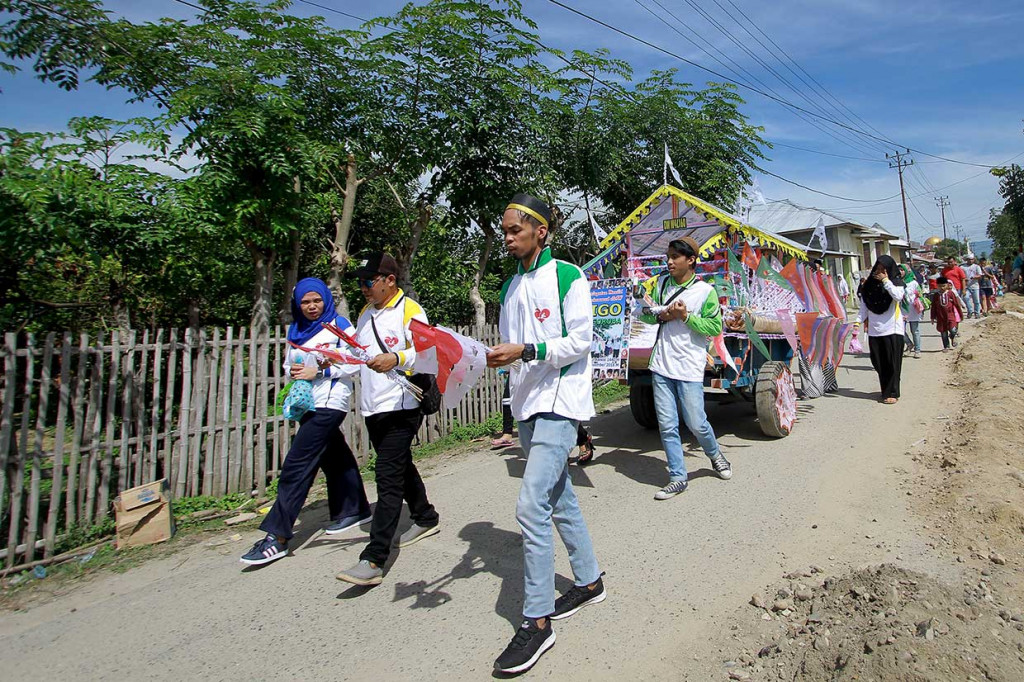 Panitia berkampung dan mendatangi rumah warga untuk membagikan paket kudapan kepada anak-anak di Kabila, Kabupaten Bone Bolango, Gorontalo, Selasa, 20 November. Panitia kegiatan Walima Goroba (Waligo) ke-21 membagikan 1.000 paket kudapan dan bendera untuk merayakan Maulid Nabi Muhammad. Antara Foto/Adiwinata Solihin
