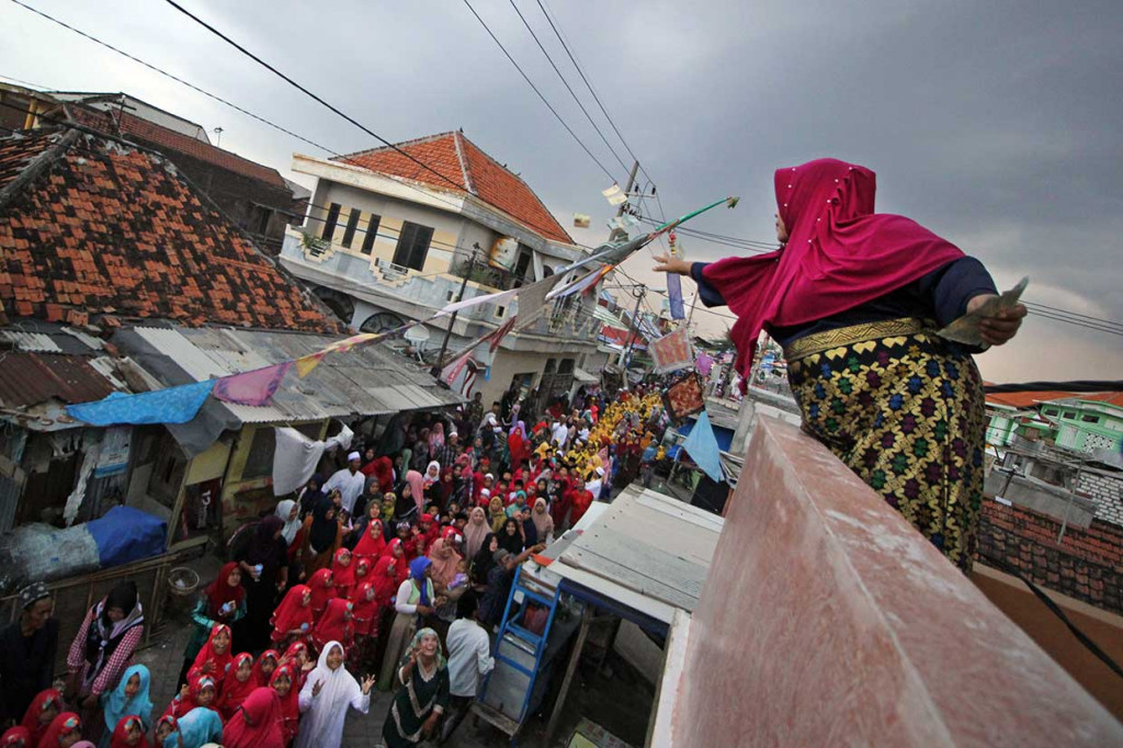 Seorang warga menebarkan uang kepada peserta pawai Maulid Nabi di Surabaya, Jawa Timur, Senin, 19 November. Antara Foto/Moch Asim