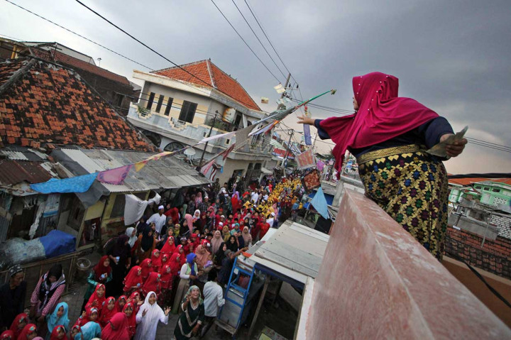 Seorang warga menebarkan uang kepada peserta pawai Maulid Nabi di Surabaya, Jawa Timur, Senin, 19 November. Antara Foto/Moch Asim