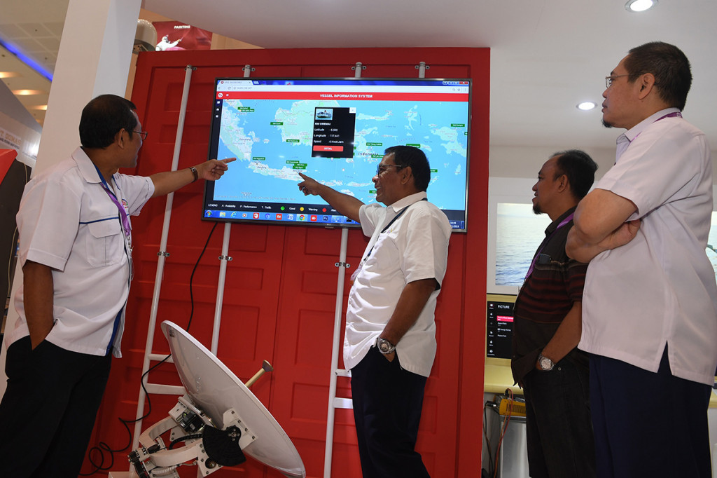 Direktur Operasi Pelni Services Asiano Y. I. Lontoh (tengah) bersama Manager IT PELNI Services Susilo Dwi (kiri) menjelaskan kepada pengunjung mengenai monitoring kapal yang ditampilkan pada The 2nd Eastern Indonesia International Maritime & Offshore Exhibition 2018. Dalam pameran tersebut, PELNI Services memamerkan salah satu produk yaitu Sistem Komunikasi Kapal (Siskomkap) sebagai bentuk service atau pelayanan kepada penumpang dalam berkomunikasi di atas kapal termasuk layanan cellular multi operator, internet maupun film.