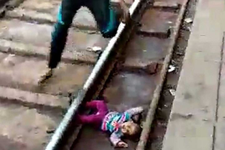 Begitu kereta api berlalu, seorang lelaki dengan cepat turun ke rel dan membopong bayi yang tengah menangis tersebut.