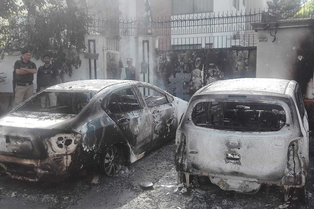 Personil keamanan Pakistan berjaga-jaga di dekat kendaraan yang hangus terbakar pascapenyerbuan sekelompok pria bersenjata di depan Konsulat Tiongkok di Karachi, Jumat, 23 November 2018.