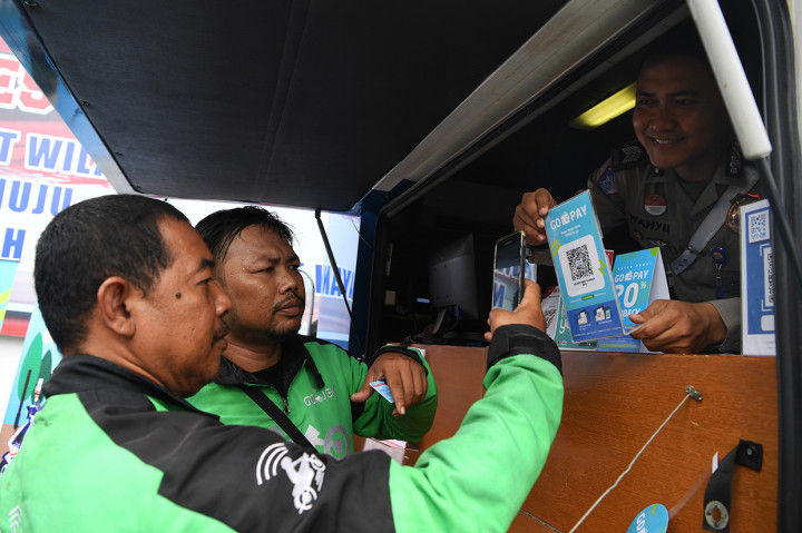 Pengemudi Go-jek melakukan pembayaran perpanjangan SIM menggunakan Go-pay pada layanan SIM Keliling seusai peluncuran program 'Cashless Payment PNBP SIM dan SKCK di Polrestabes Surabaya, Jawa Timur.