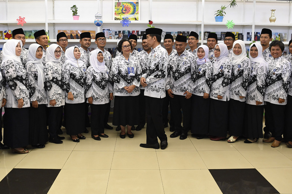 Presiden Joko Widodo bersama dengan guru penerima penghargaan pada peringatan Hari Ulang Tahun ke-73 Persatuan Guru Republik Indonesia, di Stadion Pakansari.