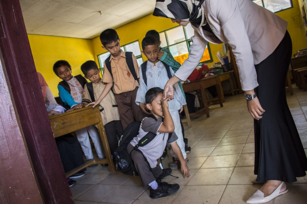 Adul berpamitan kepada gurunya seusai belajar di SDN 10 Sekarwangi, Cibadak, Kabupaten Sukabumi, Jawa Barat, Jumat (16/11/2018). Keterbatasan fisiknya tidak membuat Adul menyerah untuk belajar.