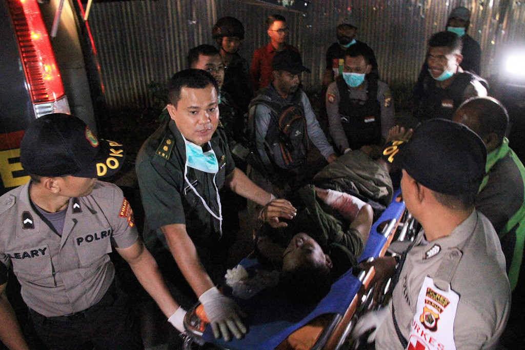 Aparat gabungan membawa anggota Brimob yang tertembak Kelompok Kriminal Bersenjata (KKB) di Wamena. Afp Photo/Anyong