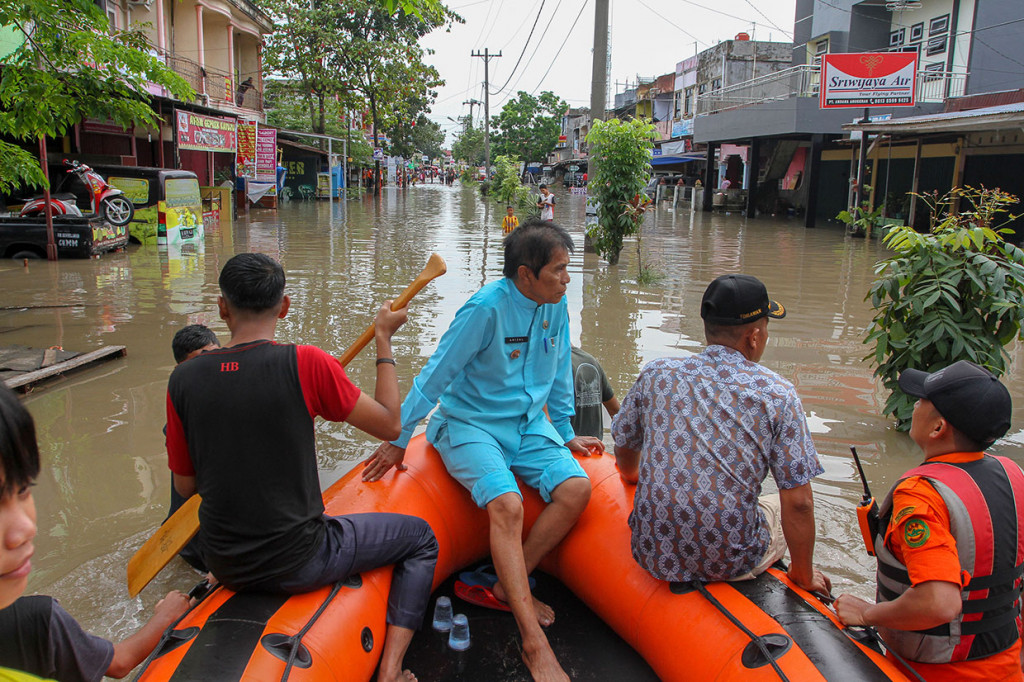 Petugas Basarnas menggunakan perahu karet mengevakuasi warga keluar dari rumahnya yang terendam banjir di Perumahan Sidomulyo, Pekanbaru.