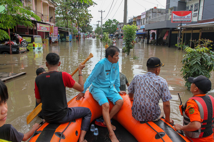 Petugas Basarnas menggunakan perahu karet mengevakuasi warga keluar dari rumahnya yang terendam banjir di Perumahan Sidomulyo, Pekanbaru.