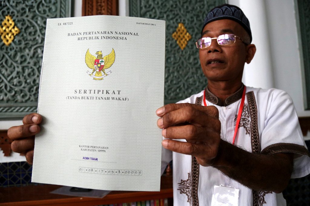 Seorang penerima memperlihatkan sertifikat tanah wakaf masjid, mushola, dan pasantren yang diserahkan Presiden Joko Widodo seusai melaksanakan ibadah Jumat di Banda Aceh, Aceh.